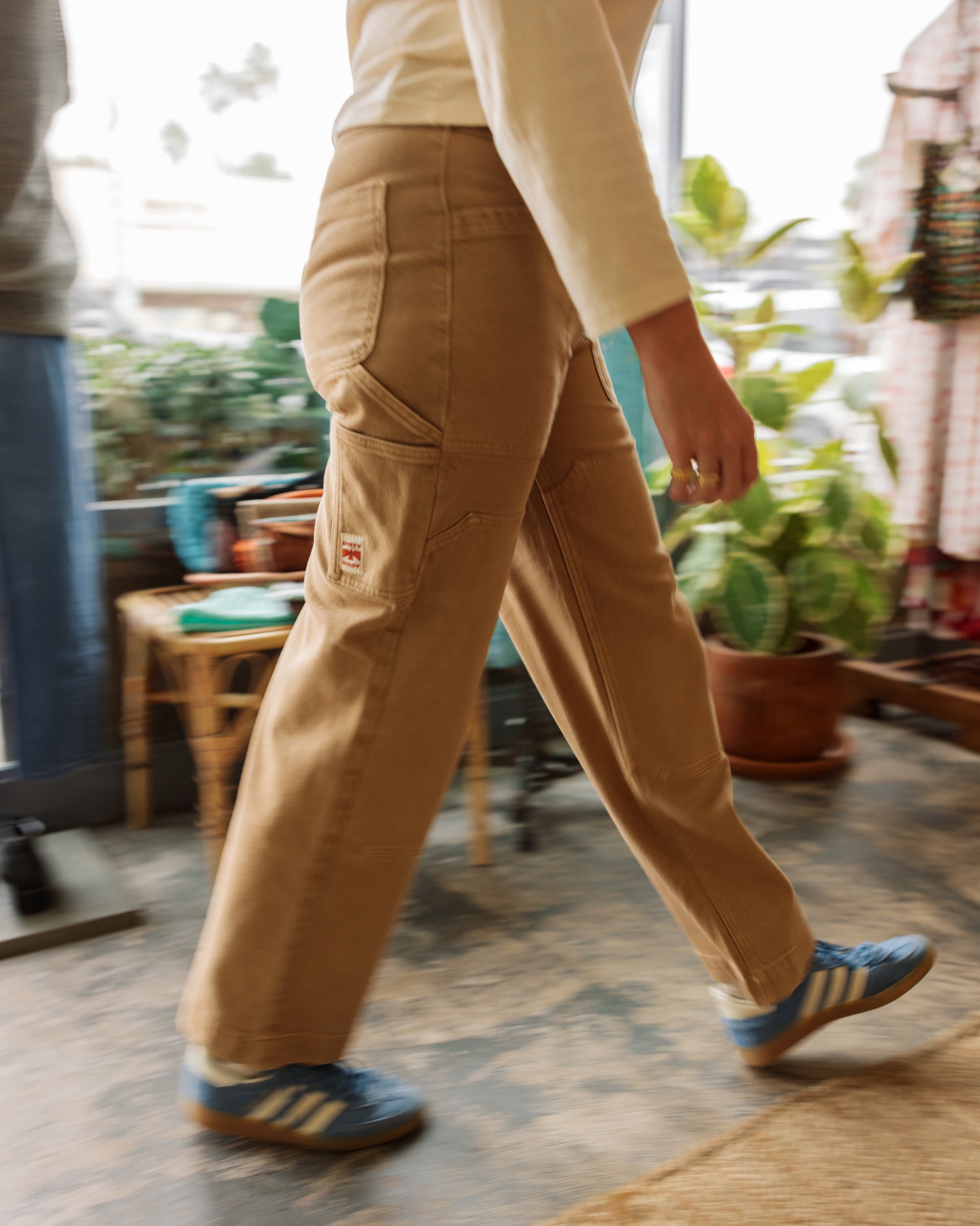 Woman in Dirty Birdy Carpenter Pant walking in a store showcasing that they are tough but also stylish enough to wear all the time.